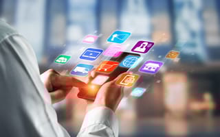 A person interacts with a smartphone surrounded by colorful, floating app icons, symbolizing digital technology and connectivity in a modern setting.