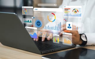 Person using a laptop with floating digital graphs and charts. Displays include bar, pie, and line charts, conveying a data analysis theme.