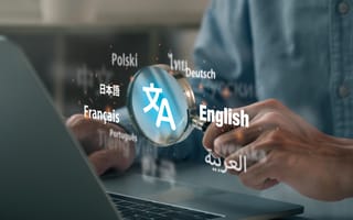 A person uses a magnifying glass over a laptop, highlighting language names like English, Français, and Deutsch, symbolizing translation and communication.