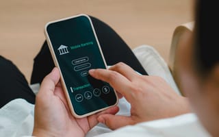 A person uses a mobile phone to access a mobile banking app, entering a username on the login screen.