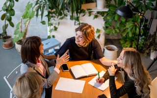 These 13 Companies Are Grounded in Powerful Missions And They’re Hiring  Four team members chat while working on a project together in an office