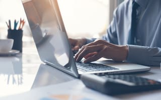 A close up of a pair of hands typing on a laptop keyboard.