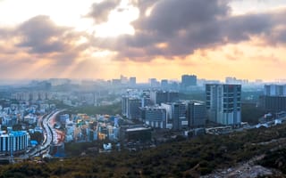 A sprawling urban landscape with high-rise buildings under a dramatic cloudy sky.
