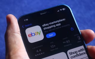 Close-up of a smartphone screen displaying the eBay app page in the App Store. A hand holds the phone, set against a deep blue background.