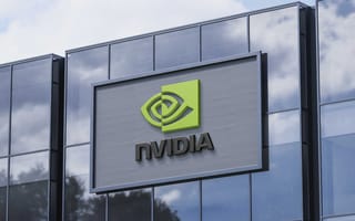 NVIDIA to Invest $100B in OpenAI as Part of New AI Infrastructure Partnership Large glass building facade with reflective windows under a partly cloudy sky. Prominent green and black NVIDIA logo, evoking a modern, tech-driven vibe.