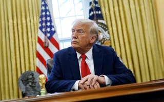 Image of President Trump sitting at a wooden desk in front of the American flag in the Oval Office.