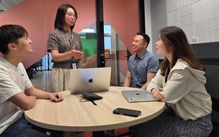 Adrian and three team members chat while working together on a project in the company’s office