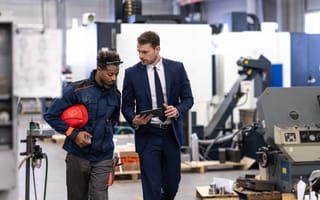 A businessman chats with a worker in a manufacturing facility