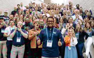 The Teamwork and Innovation Behind Cin7’s New Solutions A large group of Cin7 employees pose for a group photo while clapping and smiling