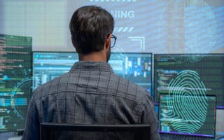 man working at multiple computer screens