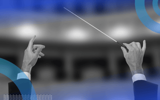 A condutor holds a baton aloft in a theatre