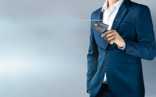 Man in suit holds up credit card.