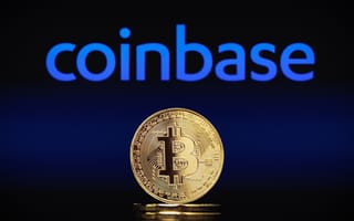 The coinbase logo in bright blue hovers over a gold coin featuring the Bitcoin logo.
