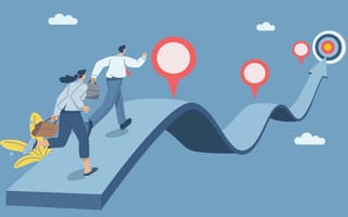 What Mission-Driven Work Means at These 6 Companies Two businesspeople running with briefcases on an undulating path while heading toward a target, symbolizing the idea of striving toward a mission as a team