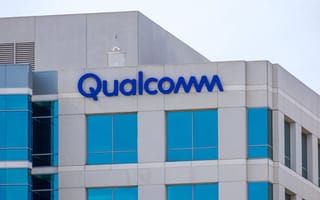 The blue Qualcomm logo on the side of a grey office building.