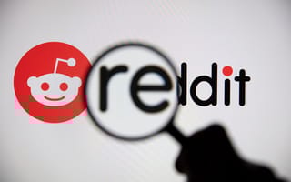A magnifying glass zooms in on the Reddit logo.