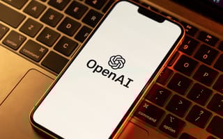 OpenAI Acquires Software Applications Incorporated, Developer of Mac App Sky Smartphone on a laptop keyboard displaying the OpenAI logo on its screen. The warm light creates a cozy, tech-focused atmosphere.