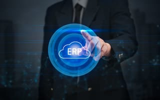 A person in a suit points to a glowing blue holographic cloud with "ERP" inside, symbolizing technology and business integration in a futuristic setting.