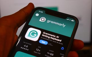 Close-up of a smartphone screen displaying the Grammarly app page in an app store. The app rating is visible, with a teal interface and a hand holding the phone.