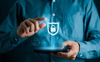 An illustration of a glowing blue shied with a padlock in the center hovers in front of a person wearing a blue dress shirt.