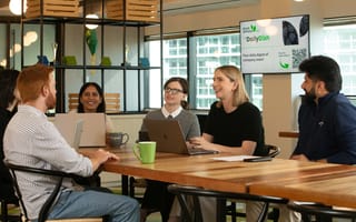 Six Ahold Delhaize USA employees sit around a meeting table with laptops