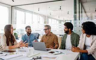 Five colleagues discuss ideas while working together on a project in an office