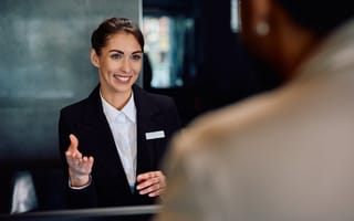 A smiling concierge wearing a blazer and name tag is pictured.