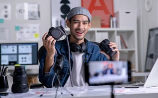 A content creator is pictured smiling at a mobile phone that's recording video.