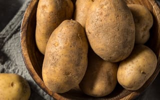 A bowl filled with brown russet potatoes is pictured.