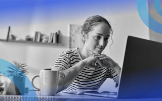 A remote worker looks at her laptop with a cup of coffee nearby