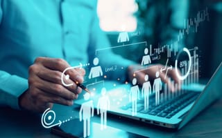 Person's hand pointing at a holographic organizational chart and data analytics overlay on a laptop and smartphone, representing business strategy and human resources.