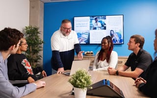 An Alliant Credit Union employee shares information with five of his colleagues while collaborating on a project in an office conference room