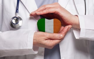 A doctor in a white coat holds a heart-shaped object with the Irish flag. A stethoscope is visible, conveying care and healthcare themes.