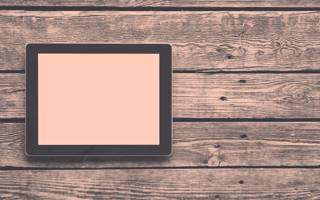 Tablet on a wooden table. It has a blank screen.