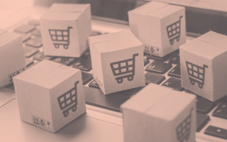 Brand vs. Growth: Why E-Commerce Companies Need to Balance Both Mini cardboard boxes with shopping carts on them sitting on a laptop keyboard.