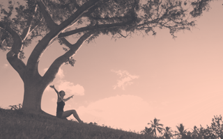 A woman celebrates gratitude under a tree