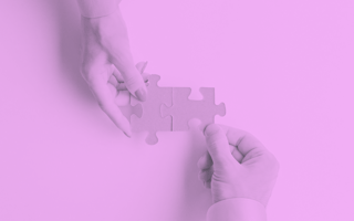 Two hands bringing puzzle pieces together.