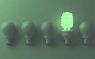 An energy efficient light lit up in a row of regular lightbulbs that are off.