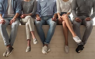 five people sitting side by side on a wooden wall