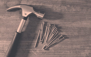 Hammer and nails resting on a wooden table.