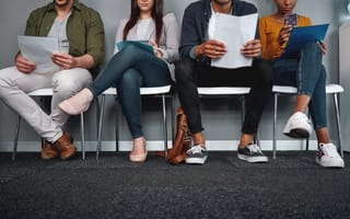 10 Tips to Improve the Efficiency of Your Recruitment Process row of interviewees in a waiting room holding pieces of paper