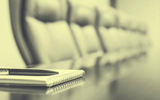 Pen and notepad sitting on an empty conference room table.