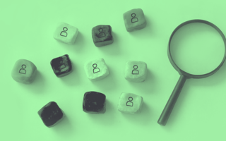 Clay blocks with figurines on them laying next do a magnifying glass.