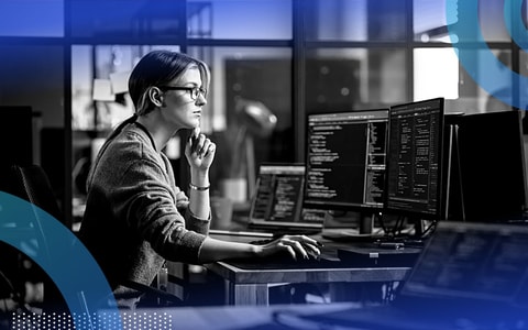 Software developer writing code on multiple screens