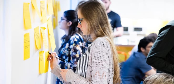 JPMorgan Chase team member writing on post-it notes on a whiteboard