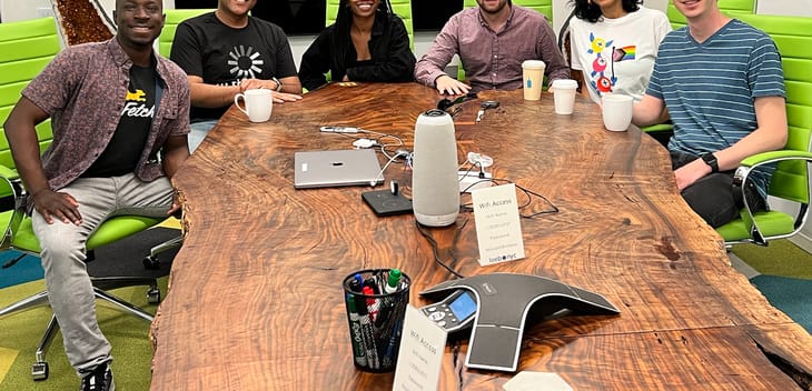 Fetch employees smile at the camera from around a conference table.