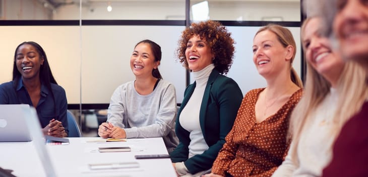 Businesswomen In Modern Office Listening To Presentation By Colleague