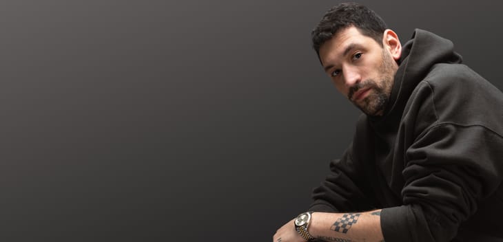 REALLY founder Adam Lyons poses for a photo against a grey ba