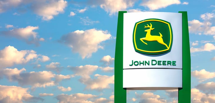 An image of a John Deere sign against a blue sky.