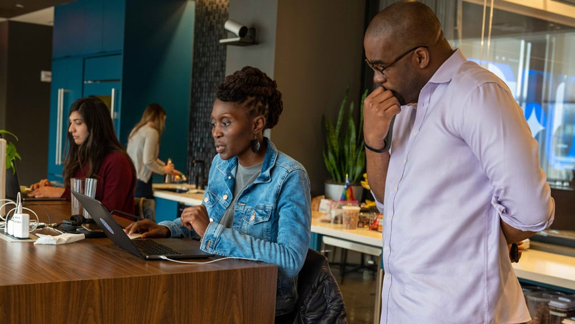 Two Coinbase team members in the office looking at a laptop